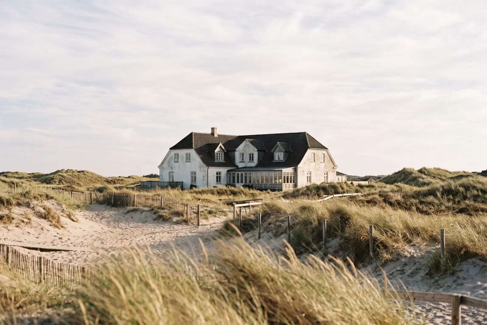 Hvidt badehotel bag lave klitter ved Vesterhavet. Lavet med AI
